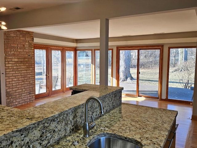 kitchen featuring wood-type flooring, light stone countertops, and sink