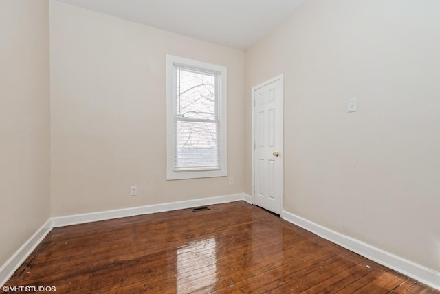 empty room with visible vents, baseboards, and dark wood finished floors