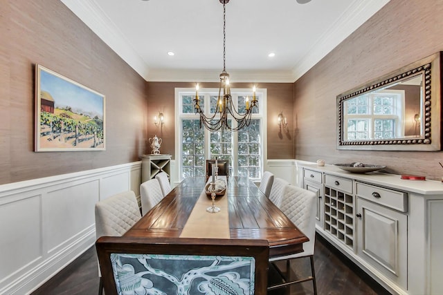 dining space featuring ornamental molding, wainscoting, dark wood-type flooring, and a notable chandelier