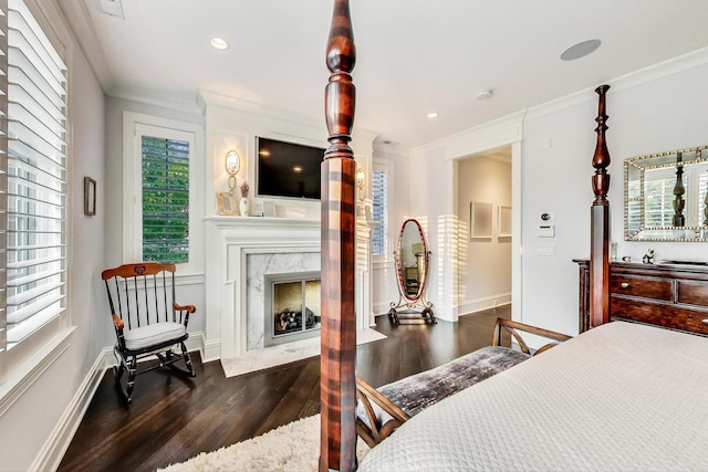 bedroom with baseboards, dark wood finished floors, crown molding, a fireplace, and recessed lighting