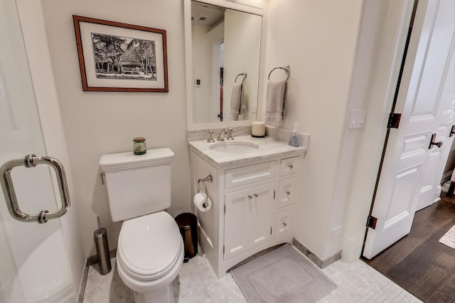 bathroom featuring toilet, baseboards, wood finished floors, and vanity