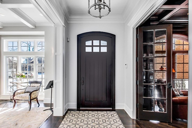 foyer entrance featuring a notable chandelier, dark wood-type flooring, baseboards, and crown molding