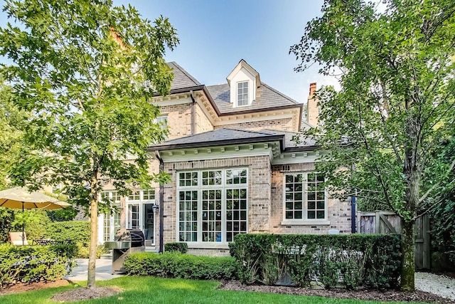 back of property featuring a high end roof, fence, and brick siding