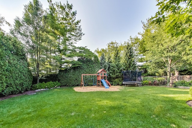 view of yard with a trampoline, fence, and a playground