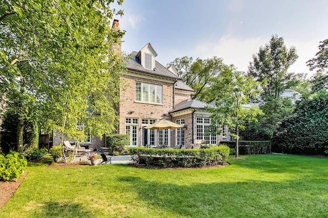 back of house with a patio, a high end roof, a lawn, and brick siding