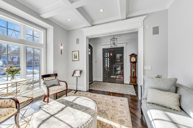 living area featuring beam ceiling, crown molding, wood finished floors, coffered ceiling, and baseboards