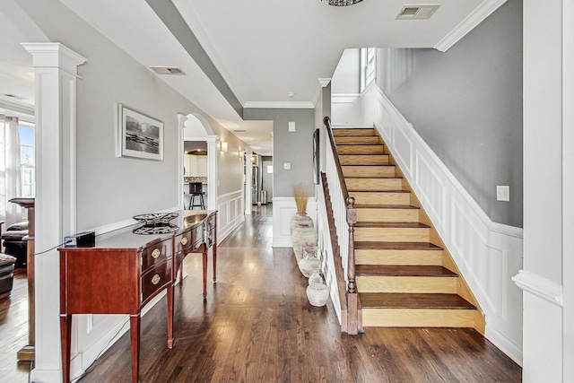 stairs featuring hardwood / wood-style flooring, crown molding, and decorative columns