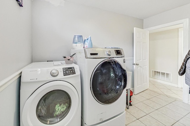 clothes washing area with washer and clothes dryer and light tile patterned floors