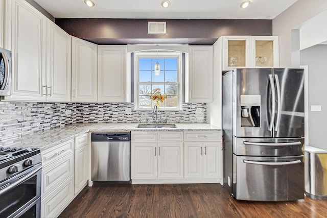 kitchen featuring sink, white cabinetry, appliances with stainless steel finishes, dark hardwood / wood-style floors, and light stone countertops