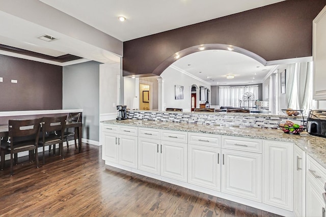 kitchen featuring crown molding, light stone countertops, dark hardwood / wood-style floors, and white cabinets