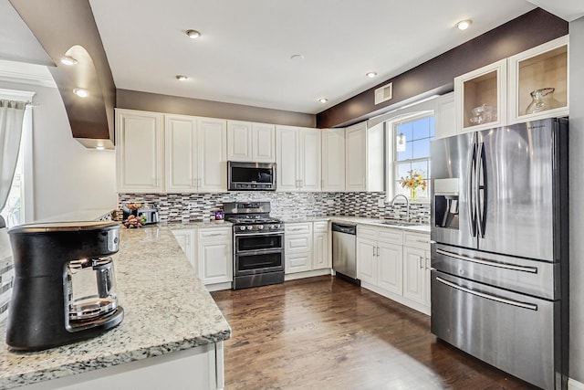 kitchen featuring sink, light stone counters, tasteful backsplash, appliances with stainless steel finishes, and white cabinets