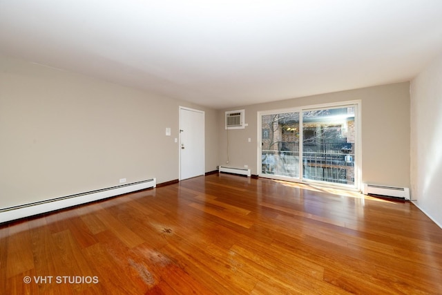 unfurnished room featuring baseboard heating, wood finished floors, and a wall mounted AC