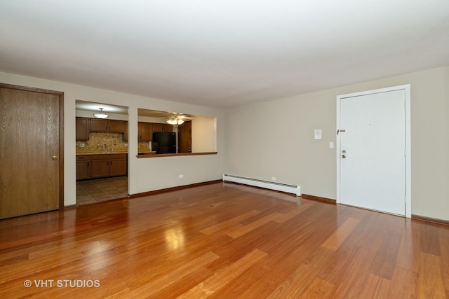 unfurnished living room featuring a baseboard radiator, baseboards, and light wood-style flooring