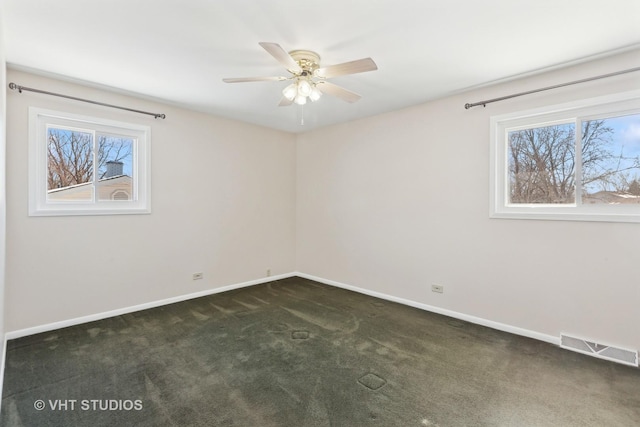 empty room featuring dark colored carpet, plenty of natural light, visible vents, and baseboards