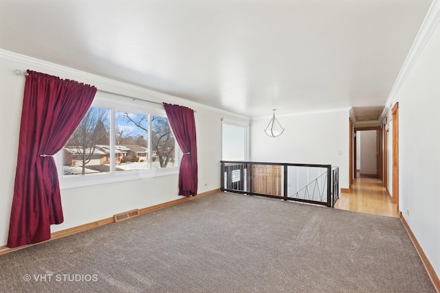 empty room with baseboards, carpet flooring, visible vents, and crown molding