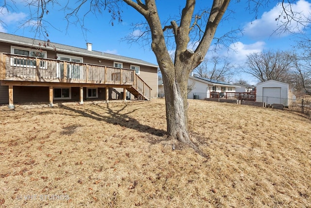 rear view of house with an outbuilding, a chimney, fence, a deck, and stairs