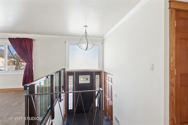 foyer entrance featuring ornamental molding, baseboards, visible vents, and carpet flooring