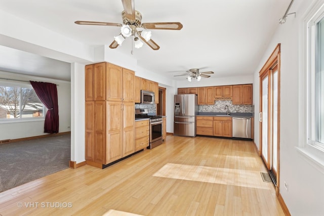 kitchen with stainless steel appliances, light wood-type flooring, a sink, and tasteful backsplash