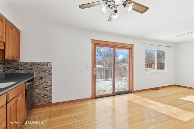 kitchen with ceiling fan, light wood-style floors, backsplash, dishwasher, and dark countertops