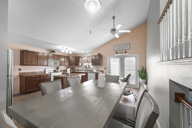 dining space with ceiling fan, high vaulted ceiling, light tile patterned flooring, and baseboards