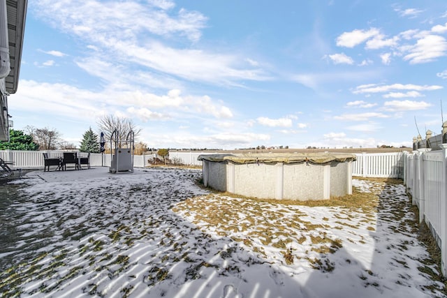 yard covered in snow featuring a fenced backyard and a covered pool