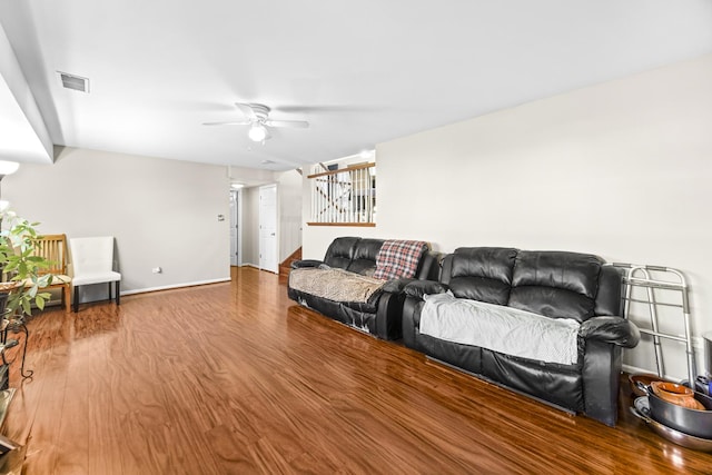 living area featuring a ceiling fan, wood finished floors, visible vents, and baseboards