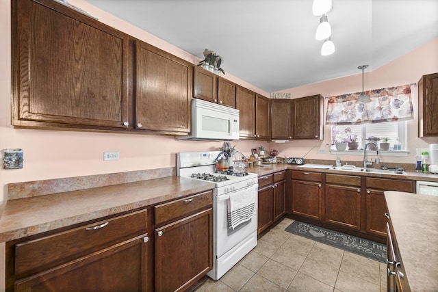 kitchen with pendant lighting, light tile patterned floors, a sink, dark brown cabinets, and white appliances