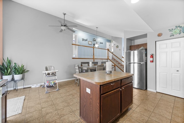 kitchen featuring freestanding refrigerator, a center island, hanging light fixtures, and light tile patterned floors