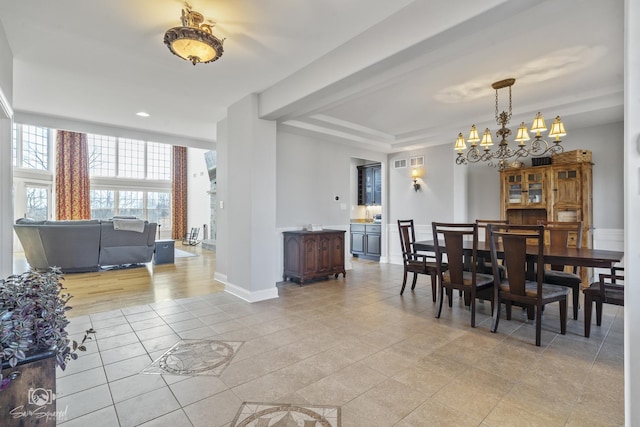 dining area with a raised ceiling, light tile patterned flooring, a notable chandelier, and baseboards