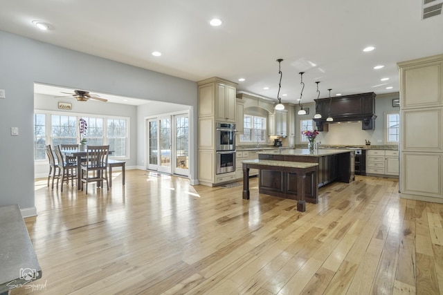 kitchen featuring visible vents, a breakfast bar area, cream cabinetry, light wood-style floors, and recessed lighting