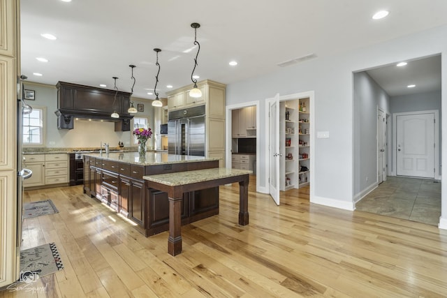 kitchen featuring light wood finished floors, visible vents, a breakfast bar, stainless steel built in fridge, and cream cabinets