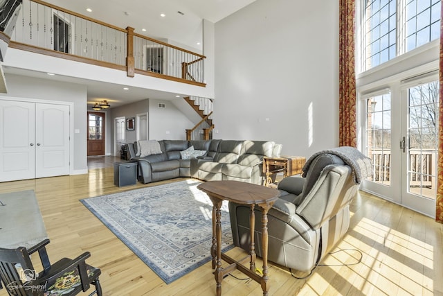 living area featuring a high ceiling, stairway, a wealth of natural light, and wood finished floors