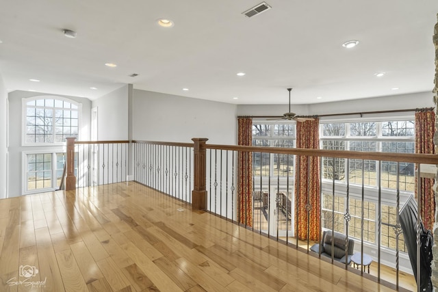 empty room with a wealth of natural light, visible vents, recessed lighting, and wood finished floors