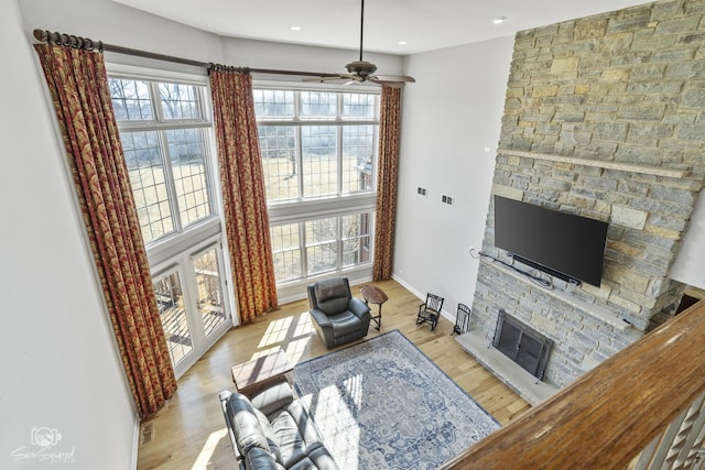 living room featuring light wood finished floors, a stone fireplace, and plenty of natural light