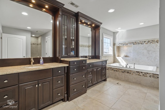 full bath featuring a garden tub, tile patterned flooring, two vanities, a sink, and visible vents