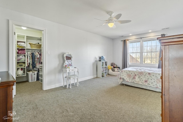 unfurnished bedroom with carpet, a walk in closet, ceiling fan, and baseboards