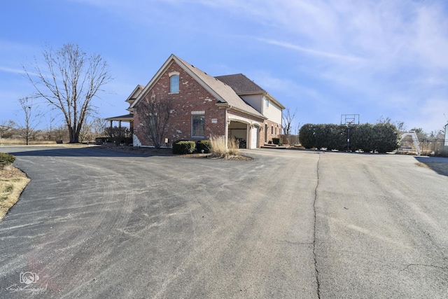 exterior space featuring a shingled roof, brick siding, and fence