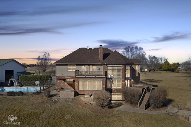 rear view of property with brick siding, a chimney, stairway, fence, and an outdoor pool