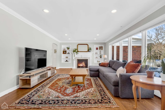 living room featuring built in features, ornamental molding, and hardwood / wood-style flooring