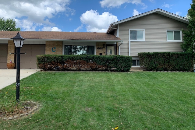 tri-level home featuring a garage and a front lawn