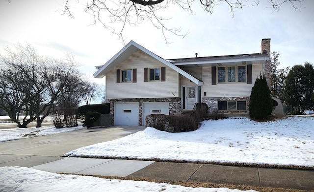 raised ranch with a garage, driveway, and a chimney