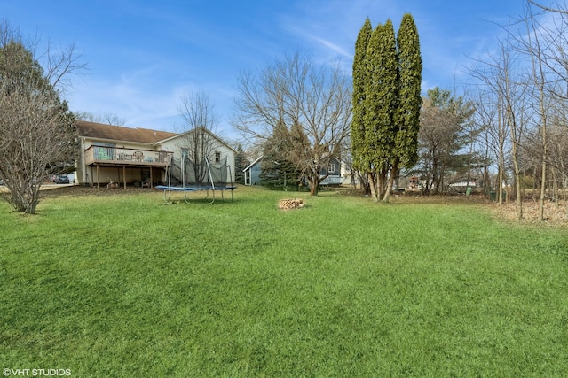 view of yard featuring a trampoline and a deck