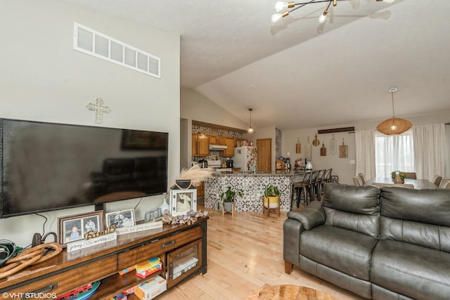 living room featuring lofted ceiling and light hardwood / wood-style flooring