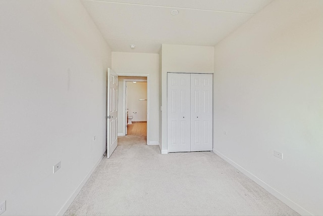 unfurnished bedroom featuring light colored carpet and a closet