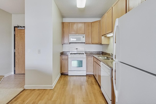 kitchen featuring sink, a textured ceiling, white appliances, and light hardwood / wood-style floors