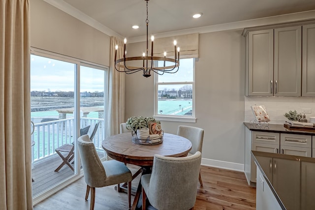 dining room with crown molding, a water view, and light wood-type flooring