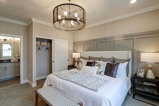 bedroom featuring ensuite bathroom, crown molding, an inviting chandelier, carpet floors, and a closet