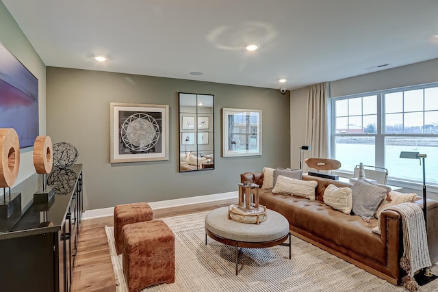 living room with a water view and light hardwood / wood-style flooring