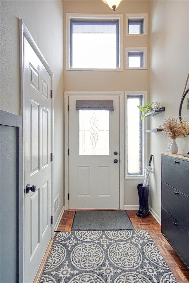 doorway to outside featuring a towering ceiling and dark parquet floors