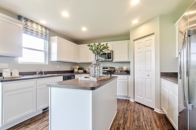 kitchen with sink, appliances with stainless steel finishes, dark hardwood / wood-style flooring, a kitchen island, and white cabinets